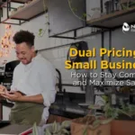 "Text reading 'Dual Pricing for Small Businesses' over a background image of a cozy restaurant interior, featuring wooden tables, chairs, and soft lighting that conveys a warm, inviting atmosphere."