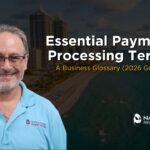 A marketing graphic featuring a clear portrait of Allen Kopelman in a light blue Nationwide Payment Systems polo shirt on the left. The background showcases a beautiful aerial coastal view of a Florida beach and high-rise oceanfront buildings. Bold white text reads "Essential Payment Processing Terms," paired with yellow subtext stating "A Business Glossary (2026 Guide)," with the company logo positioned in the lower right corner.