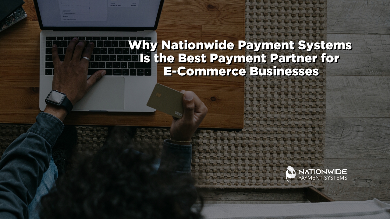 An overhead, bird's-eye view of an entrepreneur sitting at a wooden desk on a woven rug, working on a silver laptop. One hand rests on the laptop keyboard while the other holds a gold Visa credit card, preparing to input payment details. Bold white text overlays the center reading "Why Nationwide Payment Systems Is the Best Payment Partner for E-Commerce Businesses," with the white corporate logo positioned in the lower right corner.