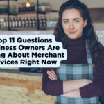 A young woman with long curly hair wearing a plaid apron stands confidently with her arms crossed in a modern cafe or boutique setting. A light blue speech bubble graphic on the left contains the text, "Top 11 Questions Business Owners Are Asking About Merchant Services Right Now," with the Nationwide Payment Systems logo in the top left corner.