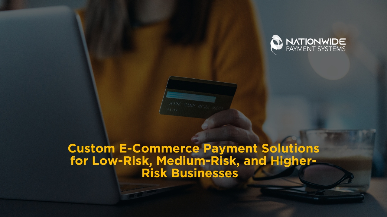 An e-commerce shopper holds a gold and dark credit card up to a laptop on a dark desk with a pair of reading glasses, a smartphone, and a glass of coffee in the background [cite: Custom E-Commerce Payment.jpg]. In the upper right corner sits the white Nationwide Payment Systems logo, and bold yellow overlay text across the lower center reads: "Custom E-Commerce Payment Solutions for Low-Risk, Medium-Risk, and Higher-Risk Businesses"