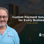 A high-authority corporate marketing graphic featuring Allen Kopelman smiling on the left, dressed in a light blue polo shirt with the Nationwide Payment Systems logo on the chest. The background shows an aerial, dim view of a Florida coastal city beach skyline with high-rise buildings and ocean water. Bold white text in the center reads "Custom Payment Solutions for Every Business," followed by "Guide (2026)" in gold lettering, with a white Nationwide Payment Systems logo placed in the bottom right corner.