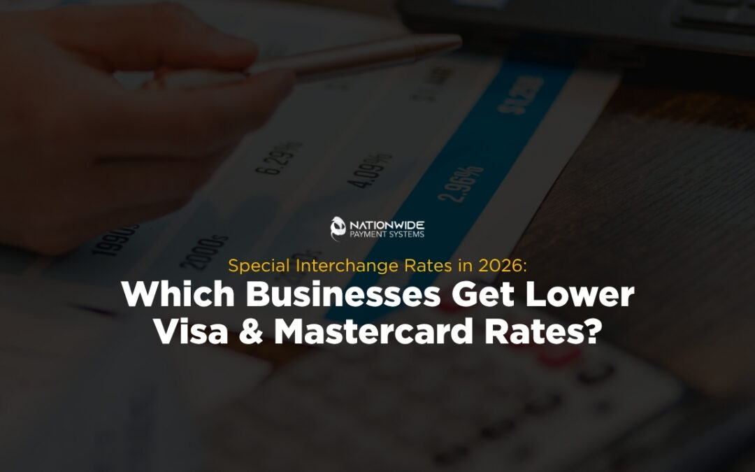 A hand holding a pen pointing to numbers on a printed financial chart alongside a desk calculator and laptop. Centered on the image is the Nationwide Payment Systems logo above yellow subtext reading "Special Interchange Rates in 2026:" and bold white text reading "Which Businesses Get Lower Visa & Mastercard Rates?"